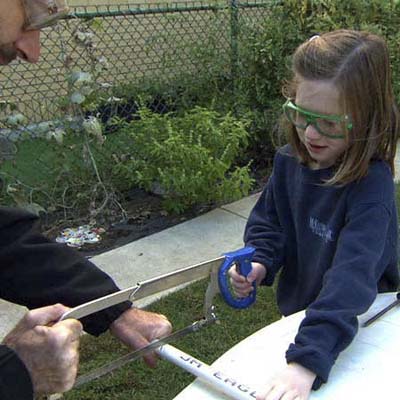 Slater Harrison and little girl cutting PVC with hacksaw