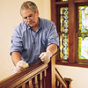 man waxing and buffing the wooden stair rail with furniture wax