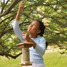 girl hanging handmade bird feeder