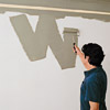 man painting W shape on the wall