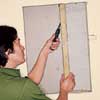 Cutting through drywall screws with a hacksaw blade, wrapped in tape at the end for a handle.