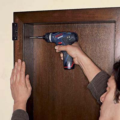 Drive drywall screws through the holes in the side of the cabinet and into the blocking