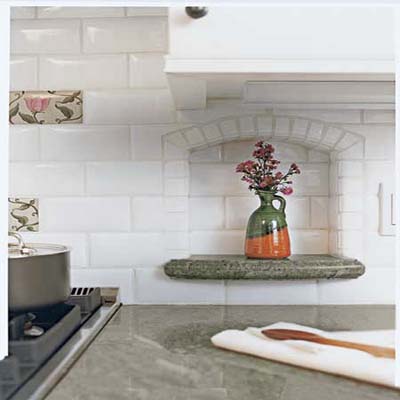 Sage-green granite countertop with arched tiled niches holds an accent piece 