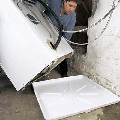 Technician installing a Drain Pan under a washer